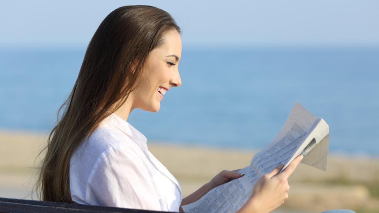Woman reading a paper at the beach.