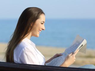 Woman reading a paper at the beach.